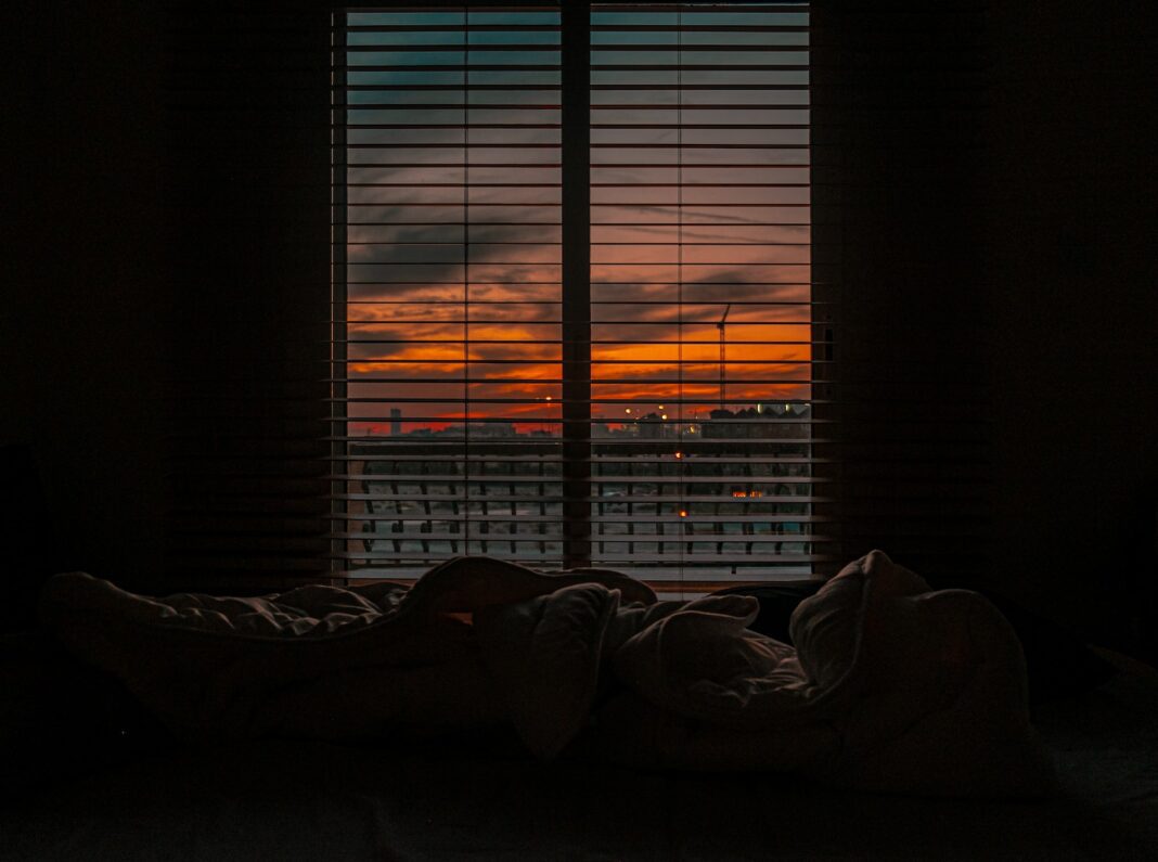 Crumpled blanket in dark room at sunset