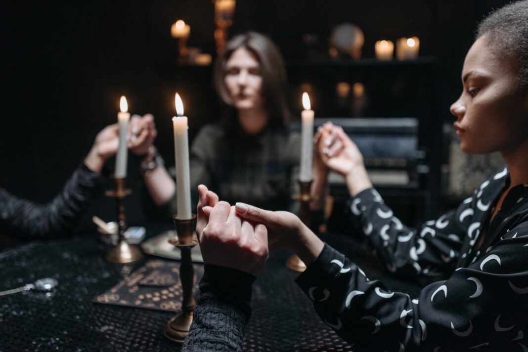 Women Holding Hands at a Table with Burning Candles